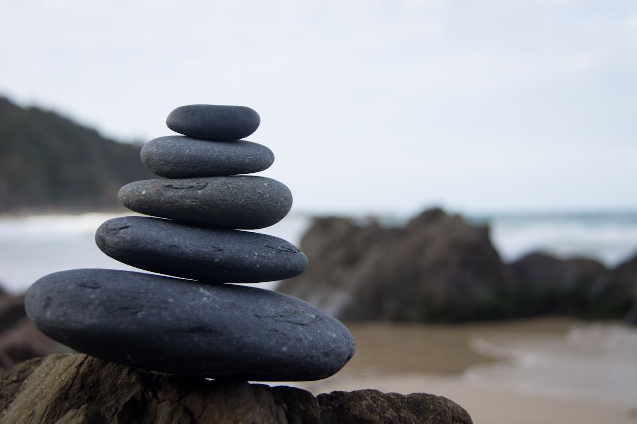 Stacked stones on a beach symbolize balance and tranquility by the ocean.